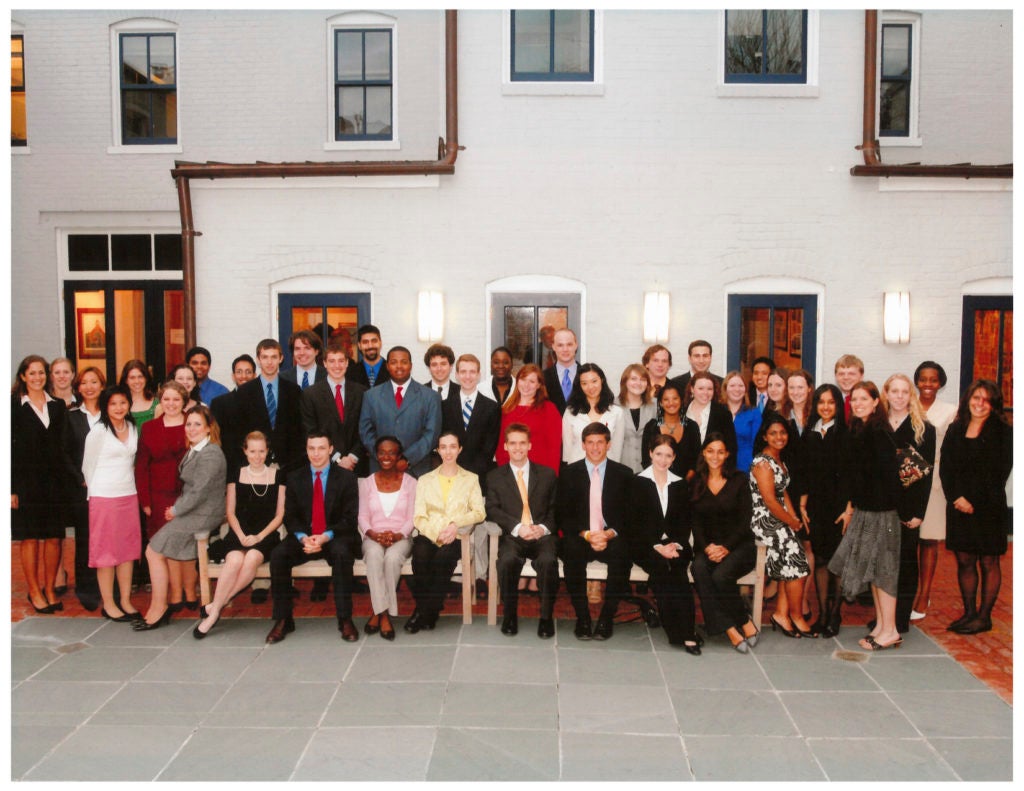 2007 Carrol Fellows, standing outside the Alumni House, wearing formal attire, smiling for the camera.