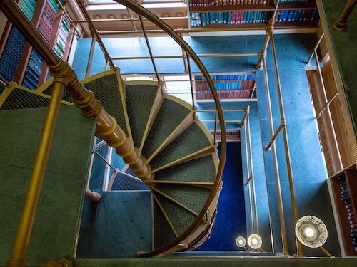 Historic Riggs Library on Georgetown University's campus with a spiral staircase and bookshelves