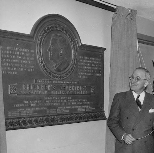 U.S. President Harry S. Truman dedicates the Children's Wing at Georgetown University Hospital in 1948, unveiling a plaque in the hallway.