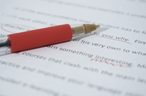 A red pen lays on top of an edited typed document