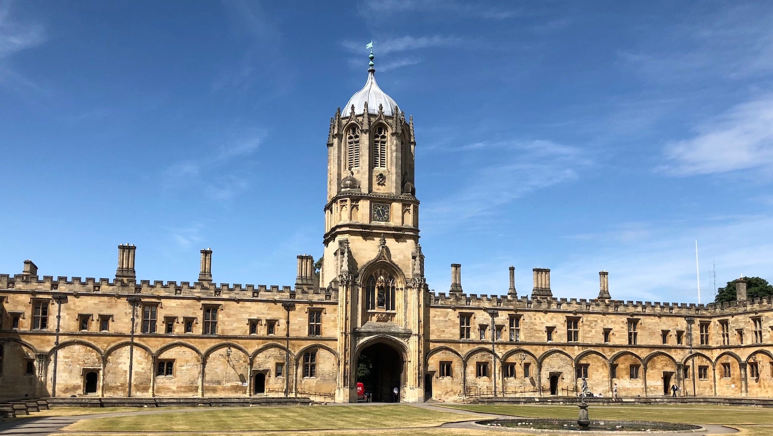 A large building at the University of Oxford with grass in the foreground and blue sky in the background