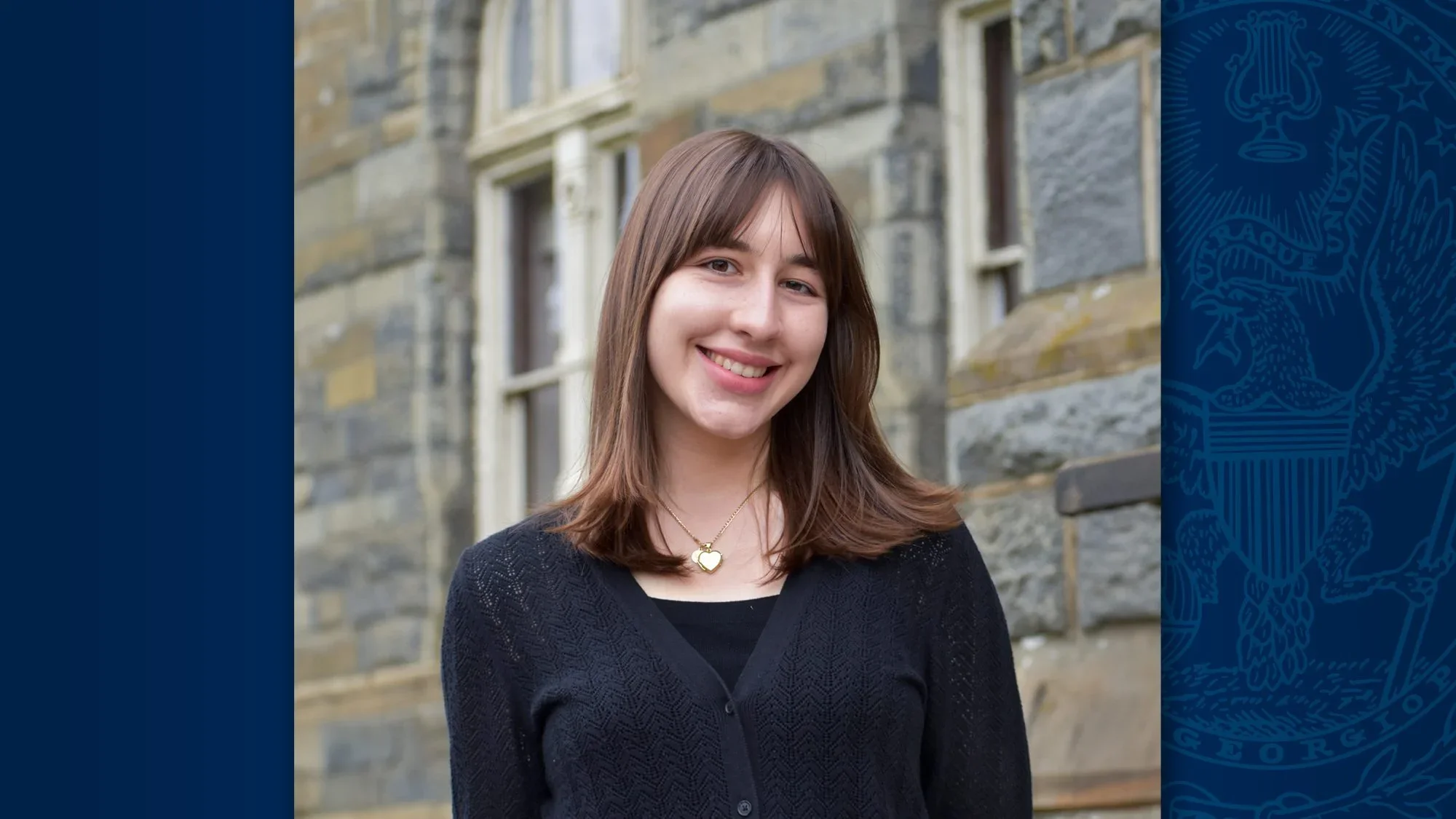A young woman with brown hair standing in front of Healy Hall and smiling.