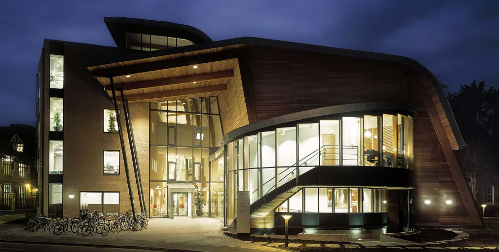 A modernist building at night with the lights on inside.